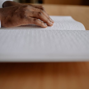 Une paire de mains lisant en braille un livre posé sur une table