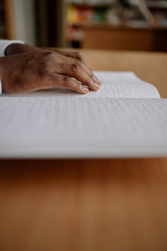 Une paire de mains lisant en braille un livre posé sur une table