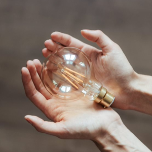 two hands holding a clear light bulb