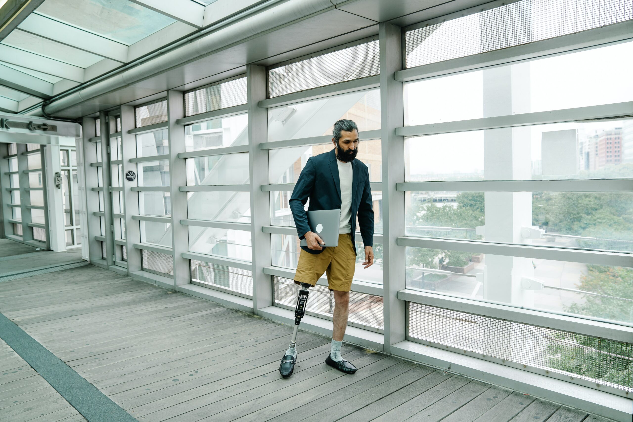 Inclusive workplace: a man with a prosthetic leg and a laptop standing on a deck.